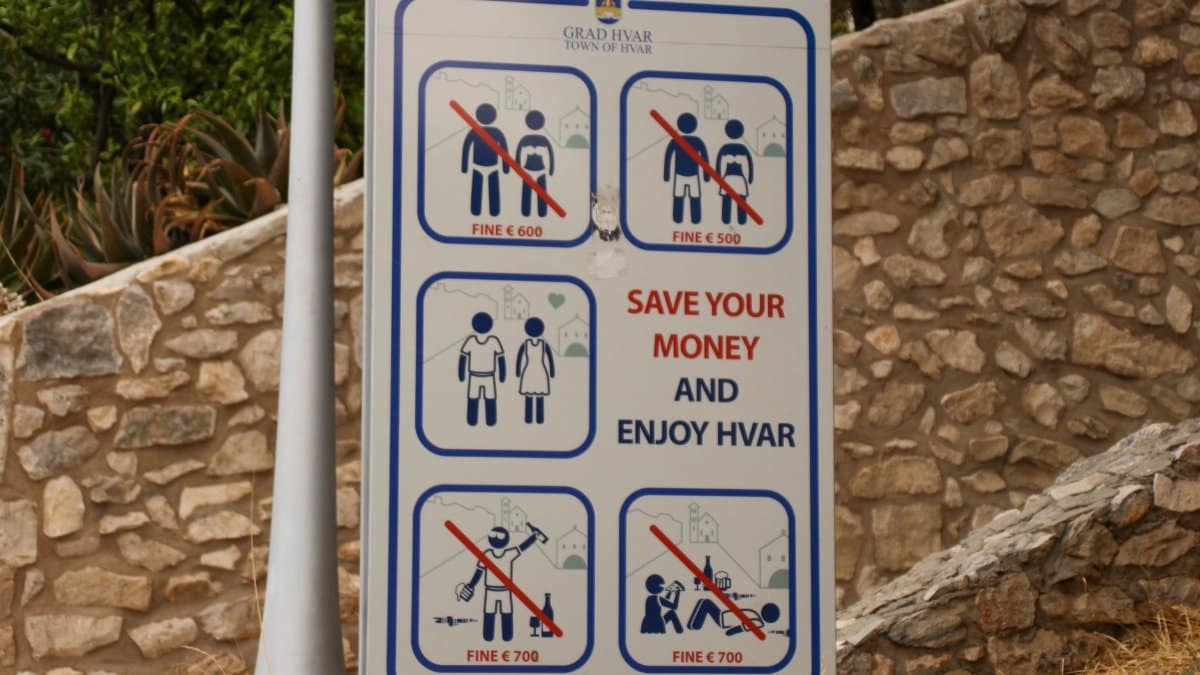 Public notice sign displaying fines for specific actions in Hvar, Croatia.