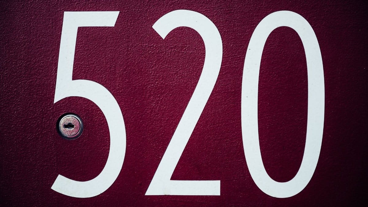 Number 520 in big white digits on rough textured red surface of door with small metal keyhole