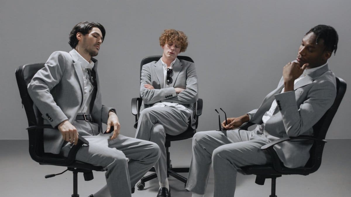 Three young professionals in gray suits collaborating in an office setting.