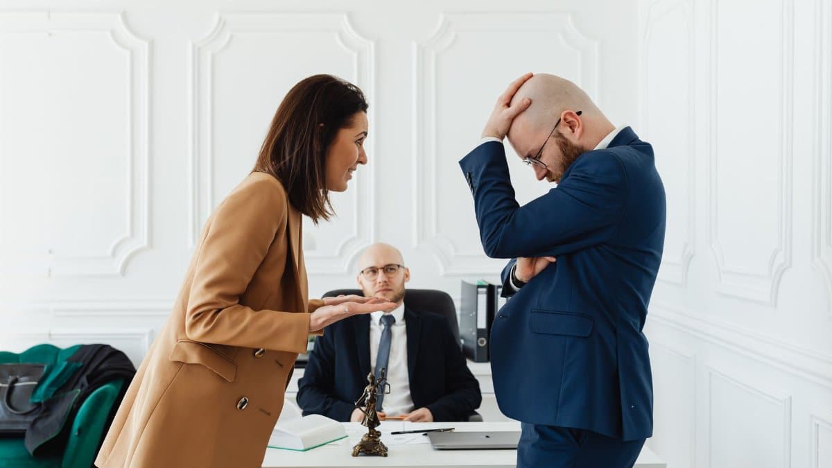 A couple having a heated argument in a law office with their attorney observing.