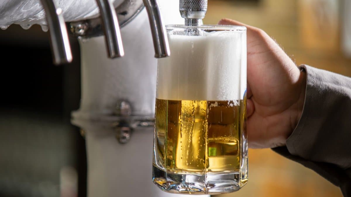 A bartender pours a cold beer into a pint glass from a tap in a São Paulo bar.