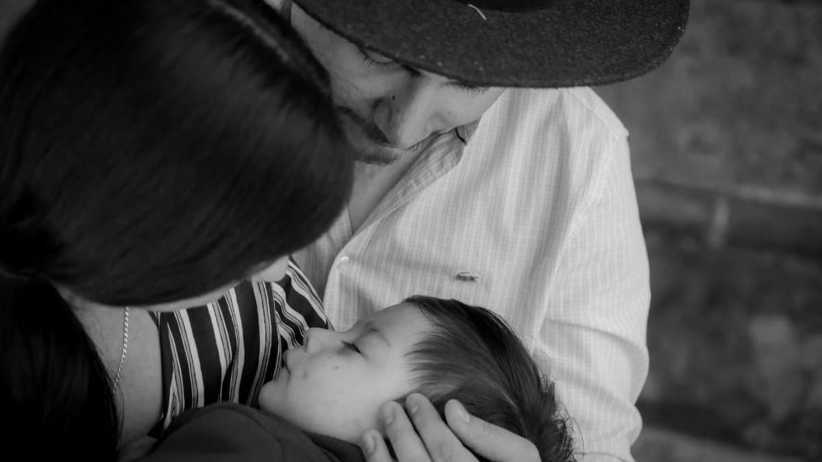 Black and white image of parents lovingly holding their sleeping child.