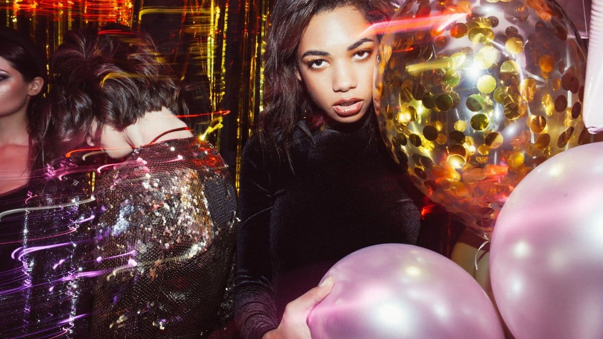 Stylish women posing with colorful balloons at a lively party.