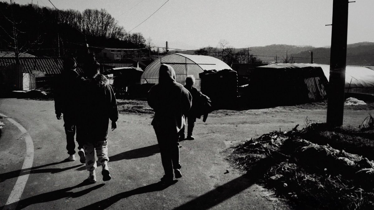 Group of people walking in a rural South Korean village, showcasing local life.