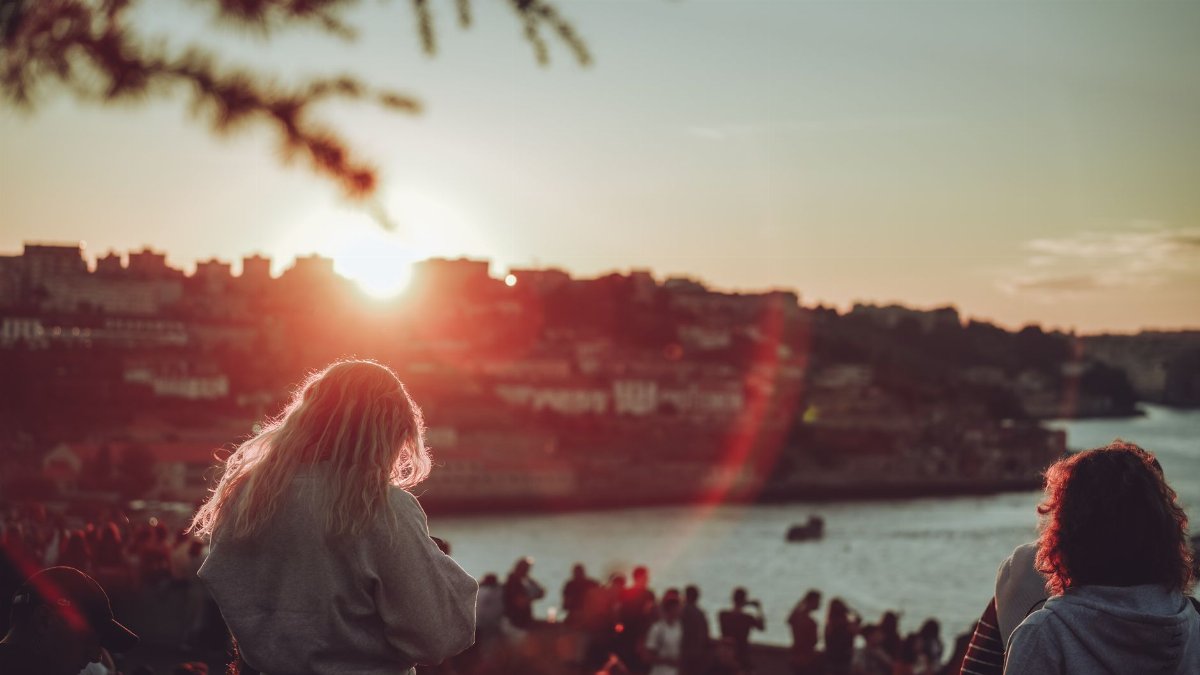 Silhouetted people enjoying a sunset over the historic city of Porto, Portugal.