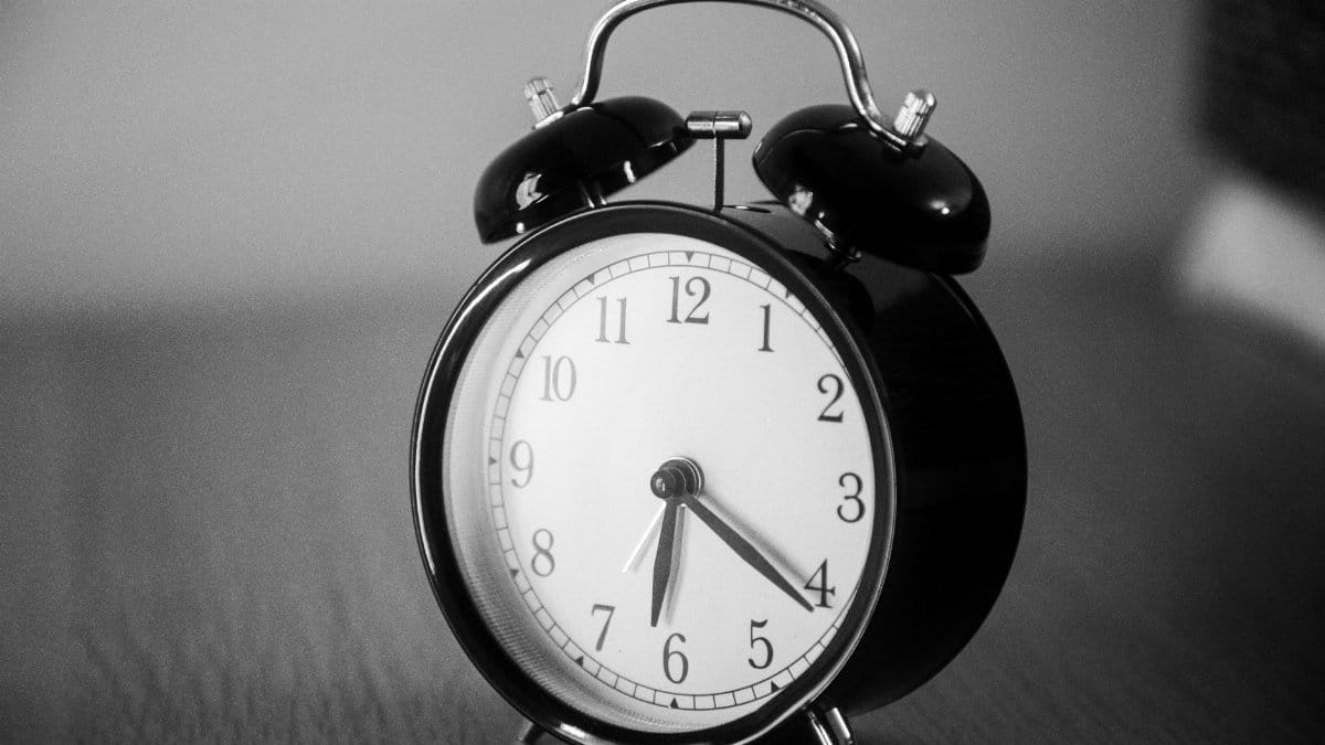 Close-up of a black vintage alarm clock showing precise time in grayscale.