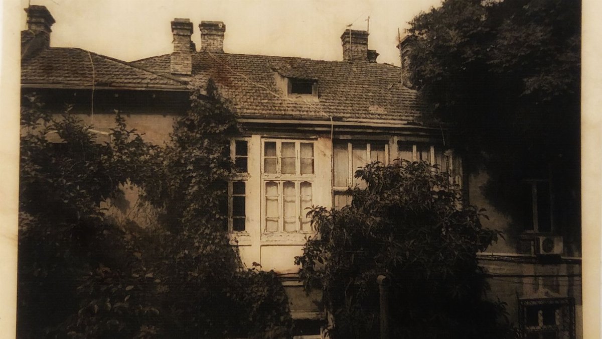 A sepia-toned vintage photograph of an old building with trees.