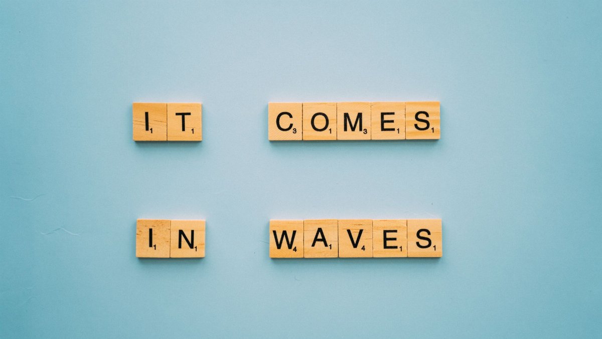 Wooden Scrabble tiles form an inspirational phrase on a blue background, conveying hope.