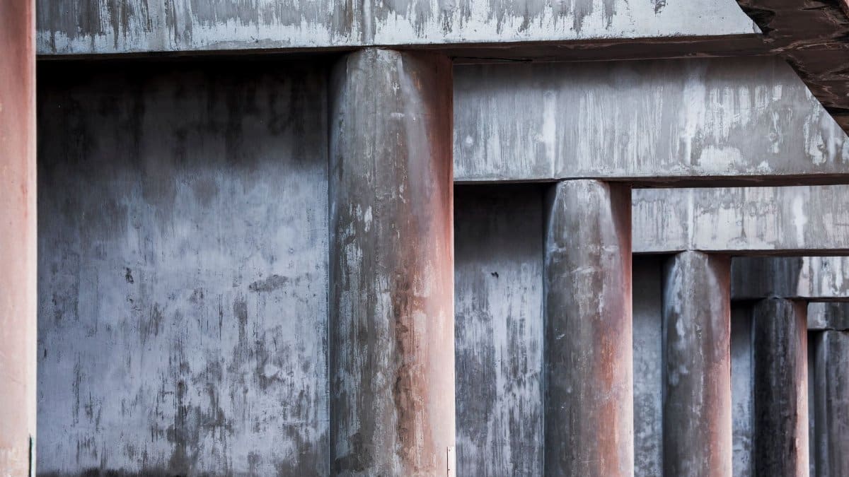 Aged concrete pillars under a bridge, showcasing decay and urban neglect.