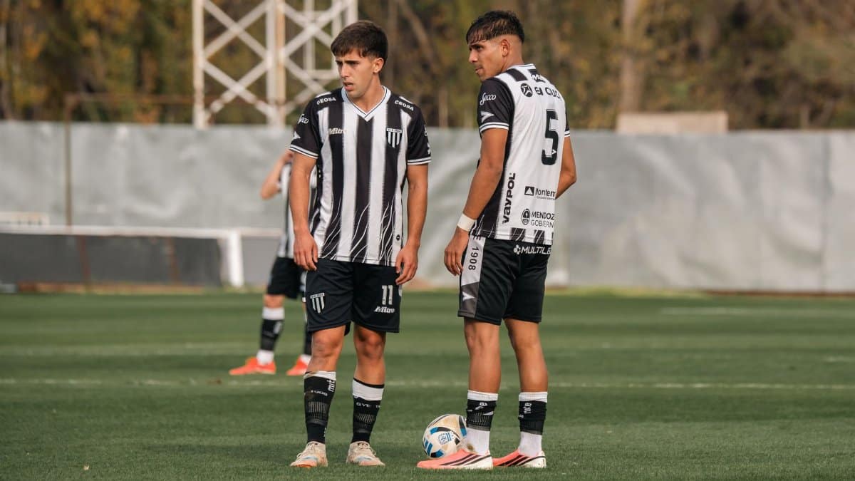 Two young male soccer players stand on a grassy field during a match.