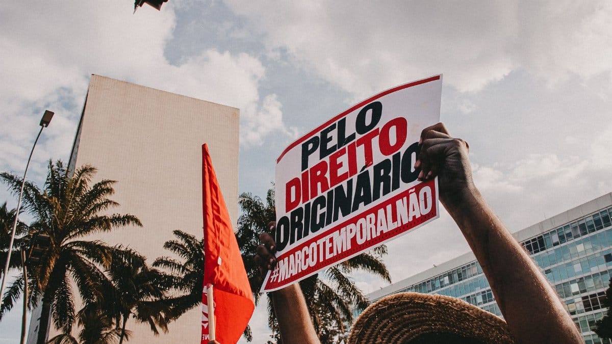 Demonstrators holding signs against Marco Temporal in city protest.