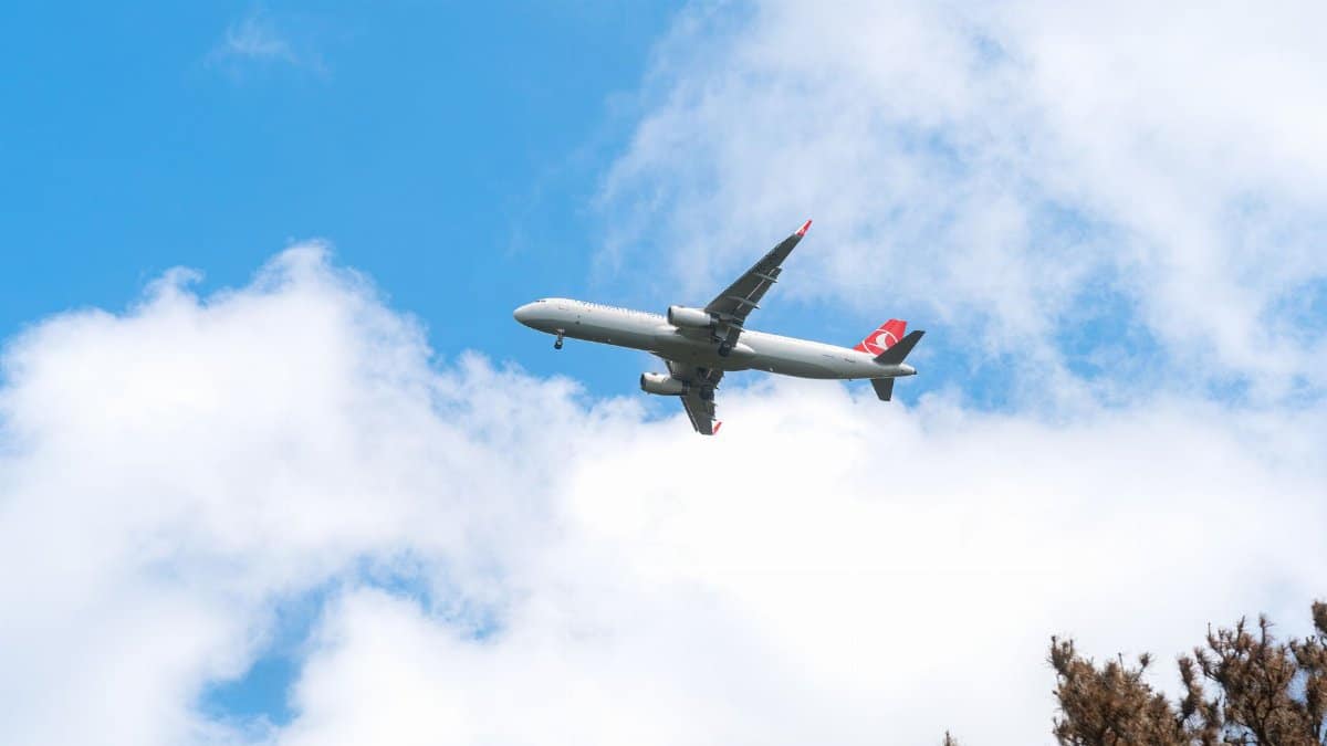 A commercial airplane glides through a clear blue sky with scattered clouds, capturing the essence of aviation travel.