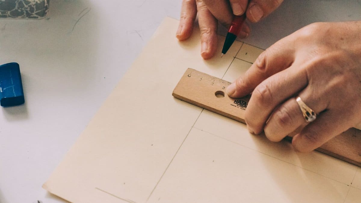 Close-up of hands using a ruler to draw lines on paper.