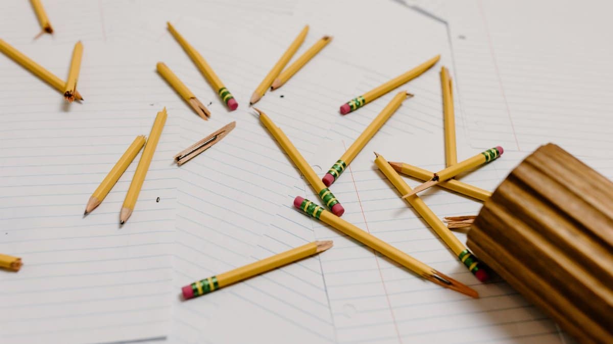 Scattered broken pencils on papers depict workplace stress or burnout.