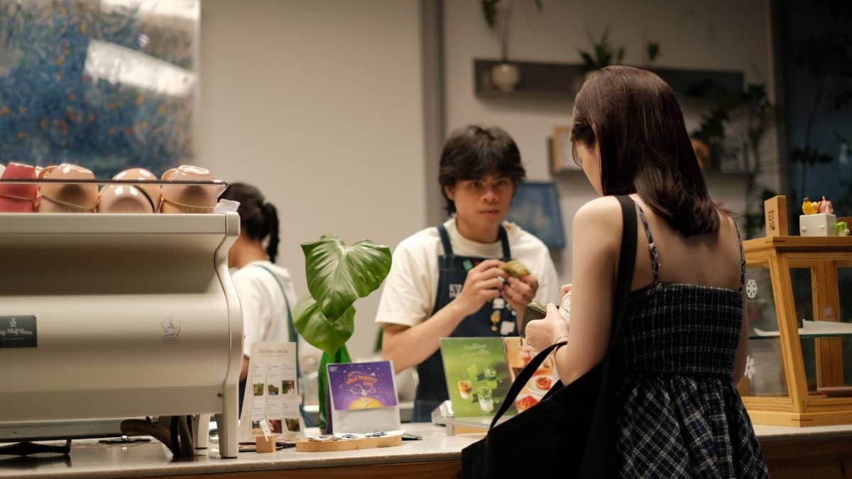Woman ordering at a cozy café counter with a barista. Warm, inviting atmosphere.