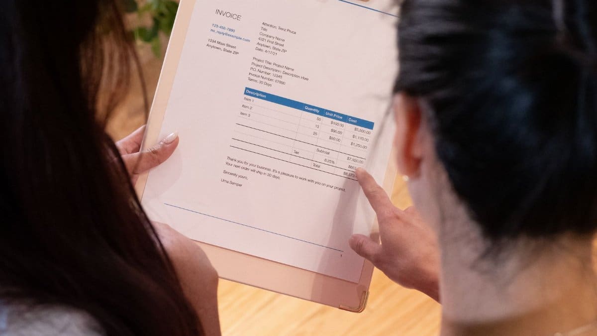 Two individuals reviewing an invoice together in a modern office setting.