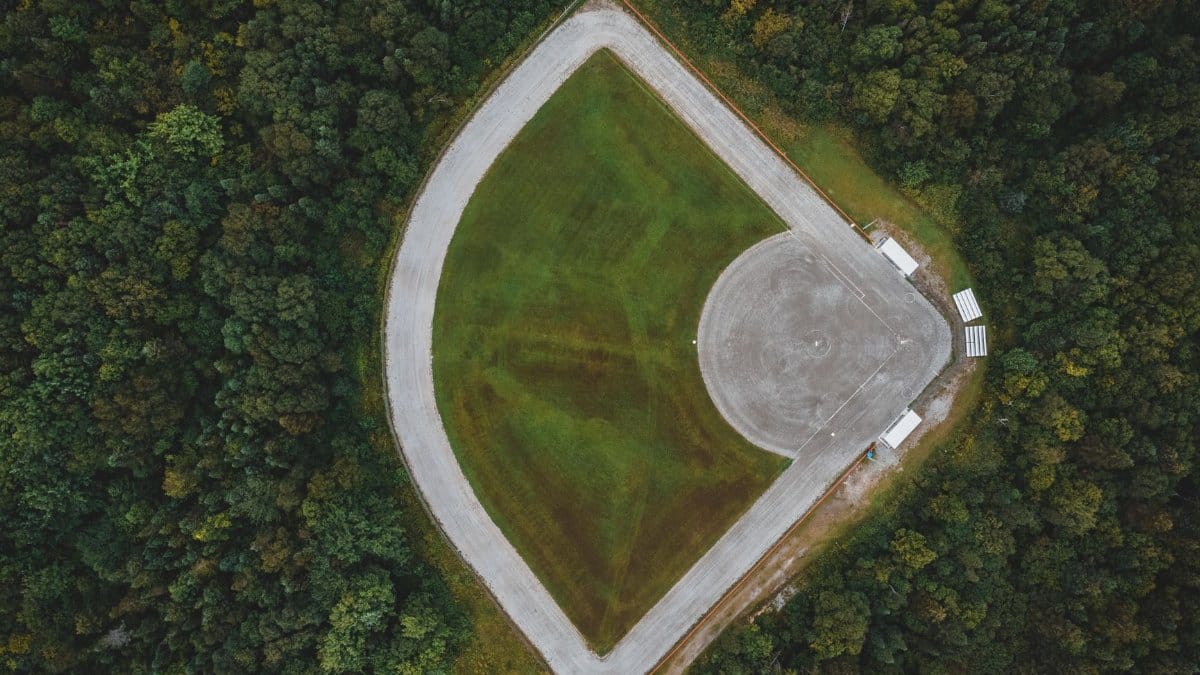 Drone shot of baseball field amidst dense forest, offering a serene and unique perspective.
