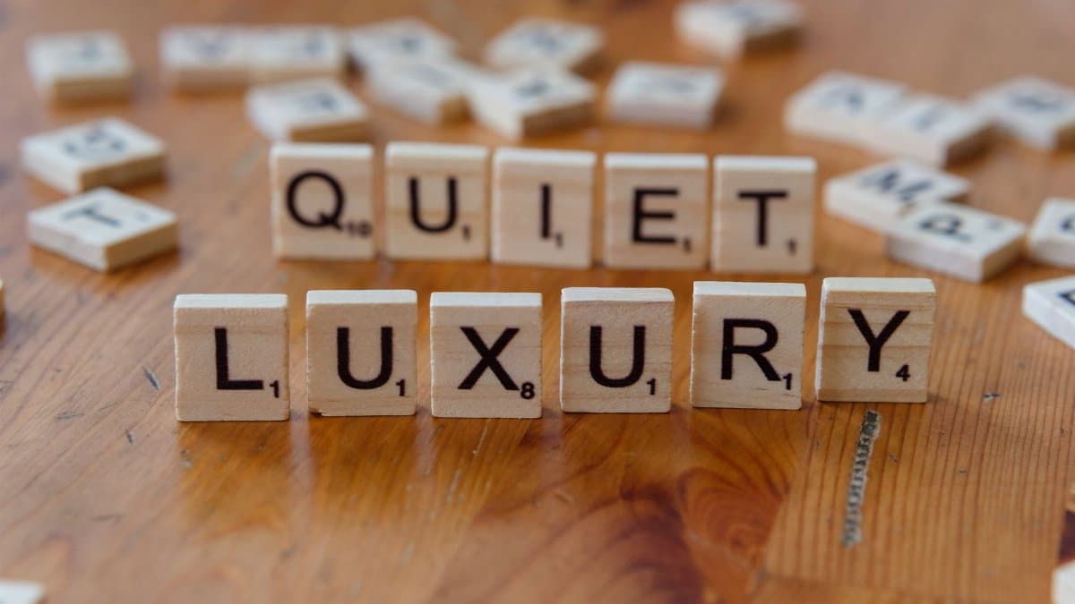 Wooden letter tiles forming the phrase 'Quiet Luxury' on a wooden table surface.