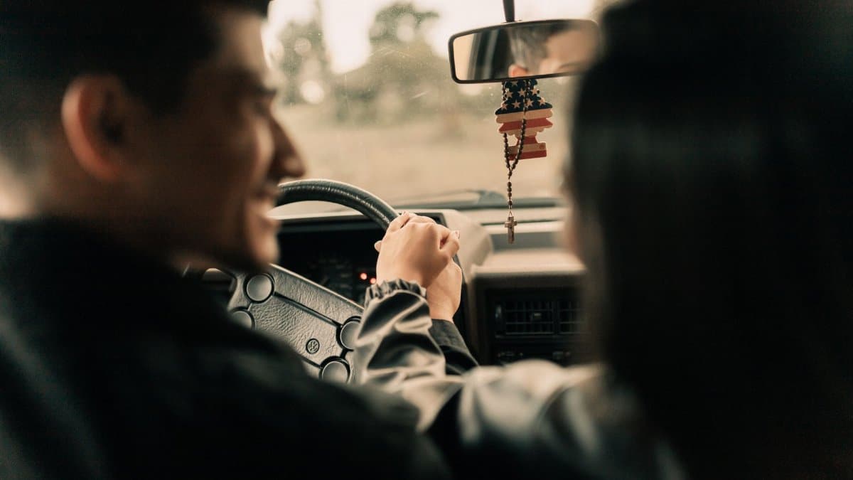 Romantic moment of a couple holding hands inside a car during a relaxed drive.