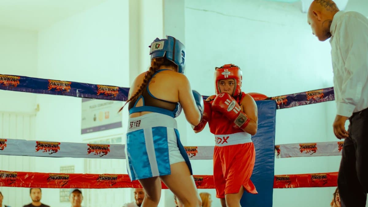 Two female boxers compete in a lively amateur match, showcasing skill and determination.