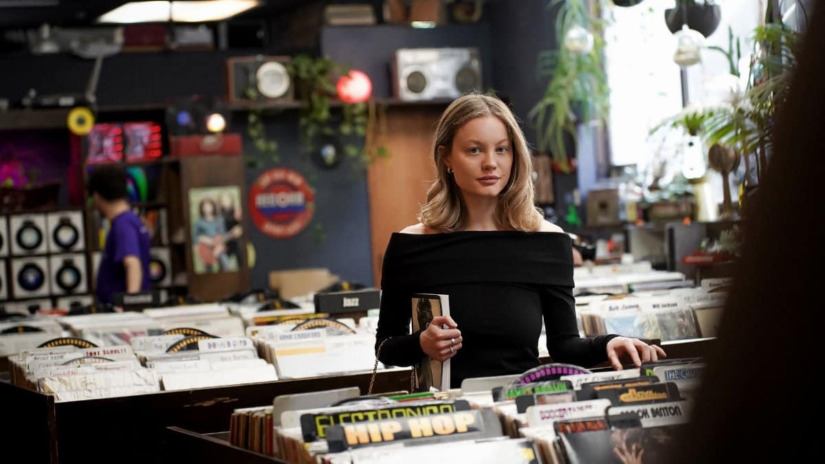 A woman looking through vinyl records in a vintage record store filled with eclectic decor.