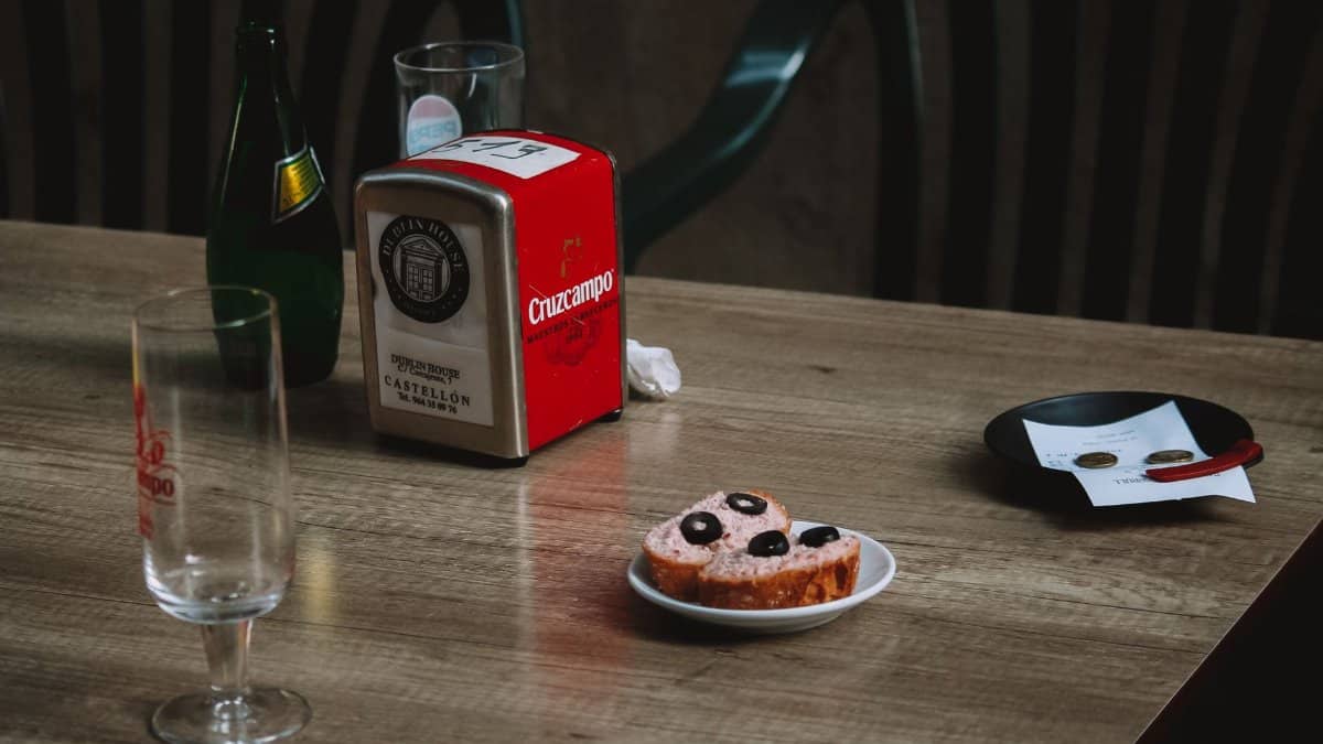 Cozy cafe scene featuring tapas, glasses, and a bottle on a wooden table for a casual dining atmosphere.