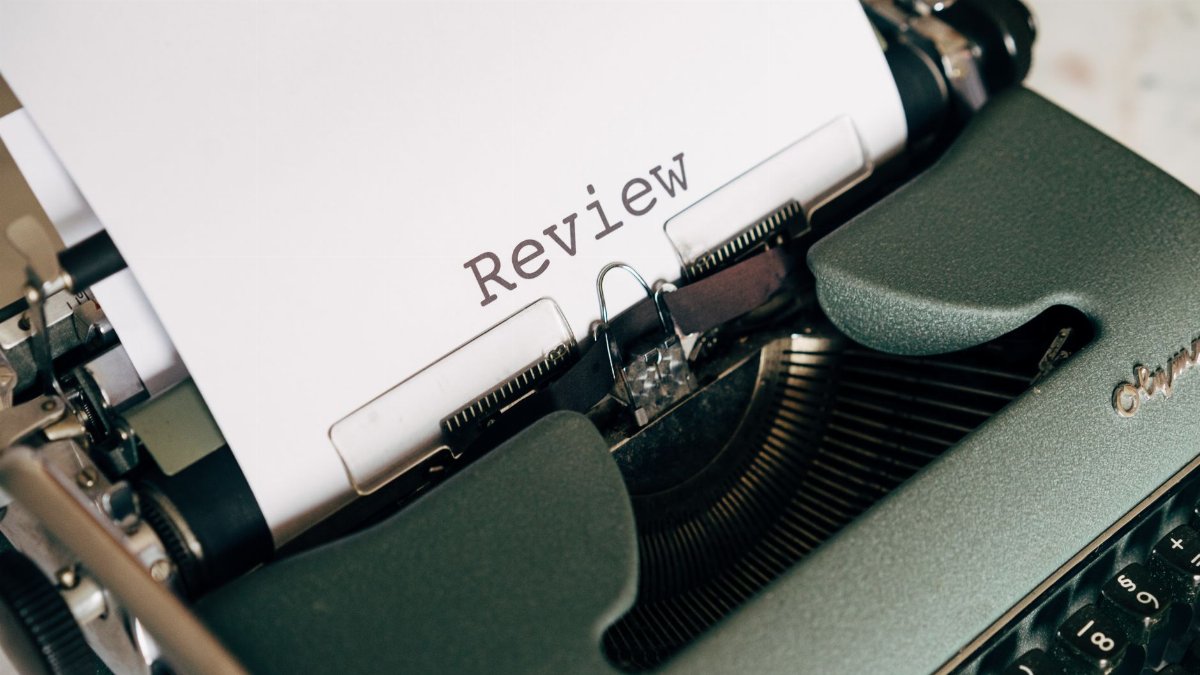 Close-up of an antique typewriter printing the word 'Review' on white paper.