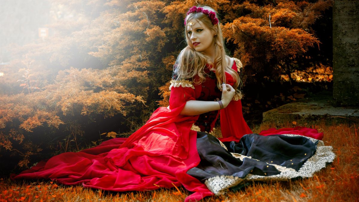 A captivating scene of a woman in medieval costume posing in a vibrant fall forest.