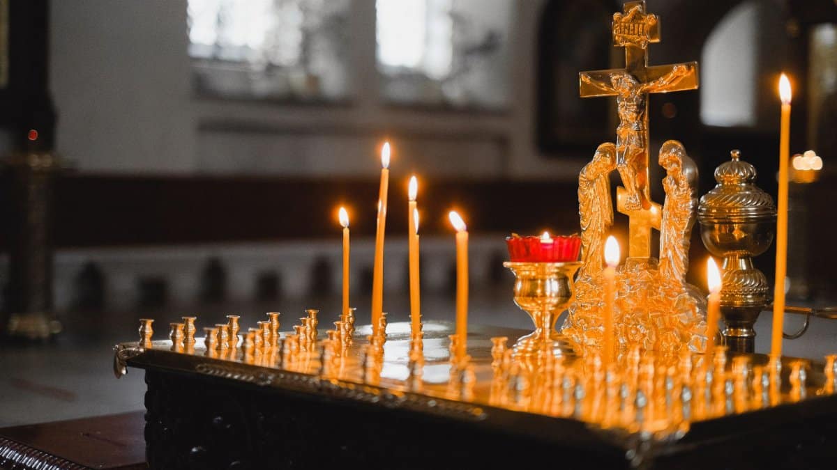 A serene church scene with lit candles and a golden crucifix, highlighting spiritual ambiance.