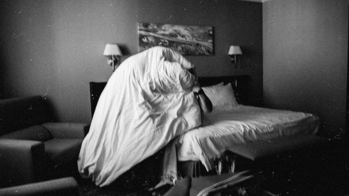 Intriguing black and white photo of a bedroom with a duvet in motion.