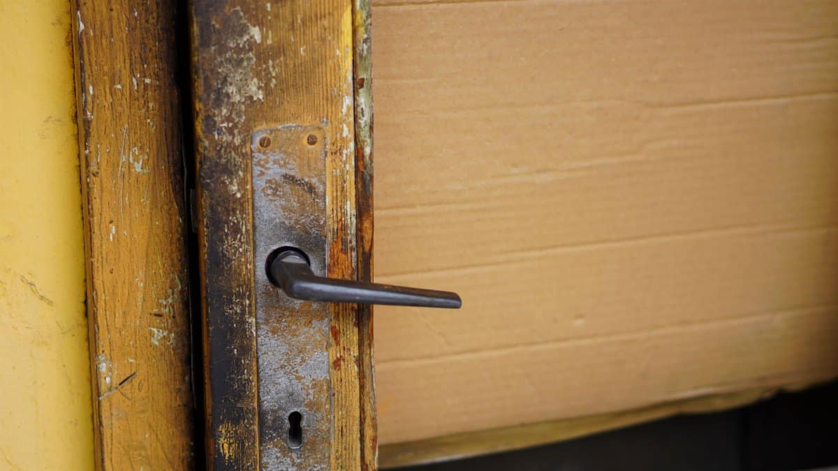 Close-up of a weathered wooden door with a vintage metal handle, showing rustic charm.
