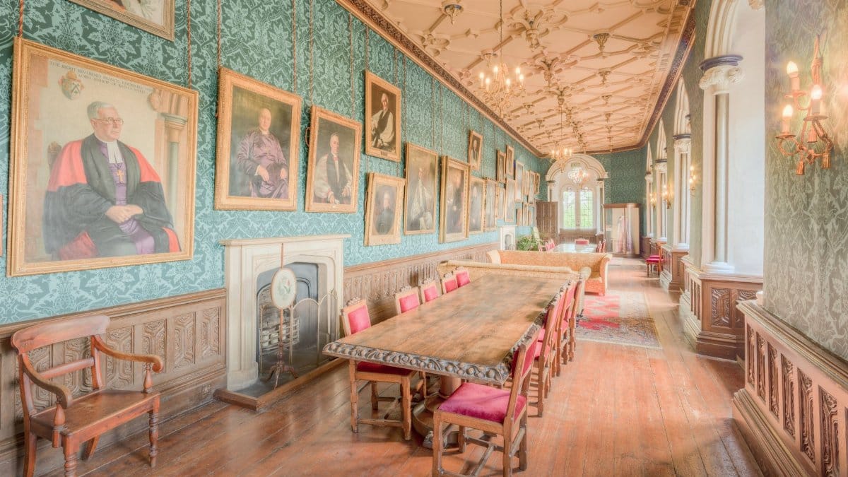 Historic corridor in England with ornate decor and framed portraits, showcasing classic British interior design.