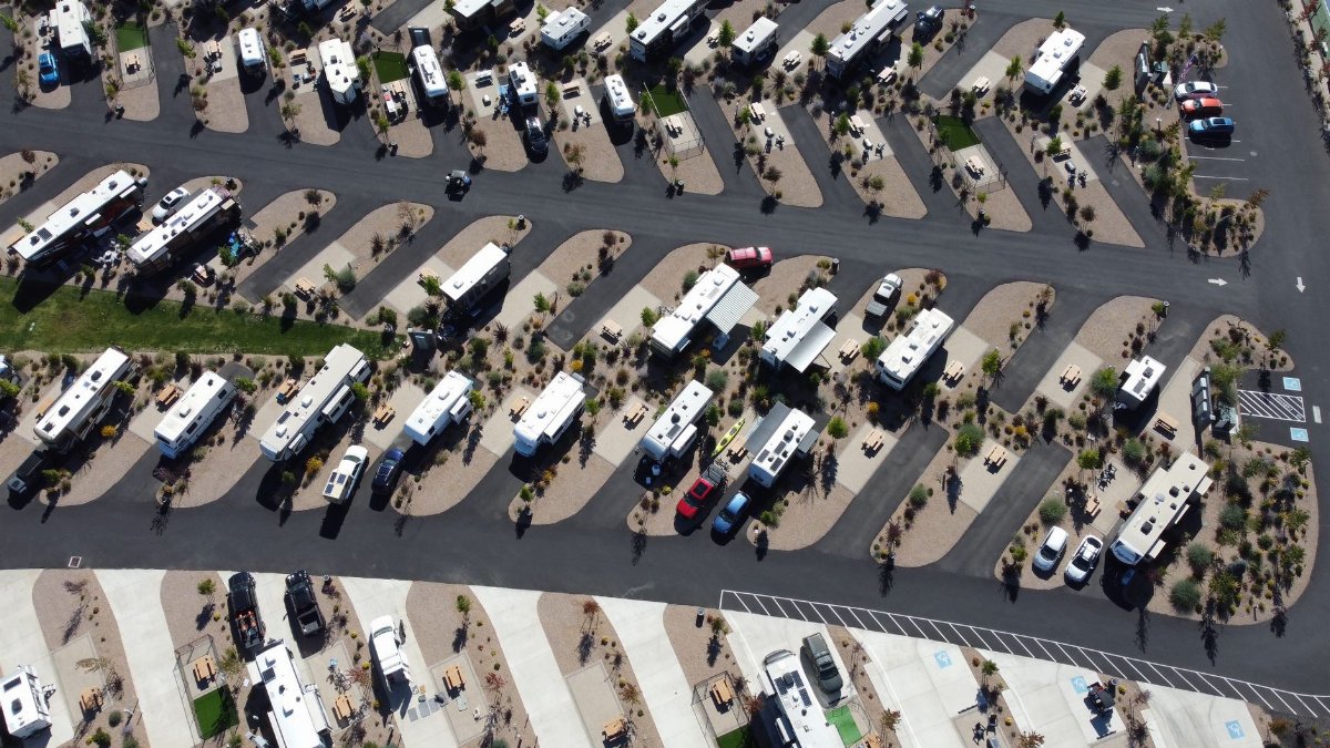 Aerial view of a spacious RV park with several campers and vehicles in designated spaces.