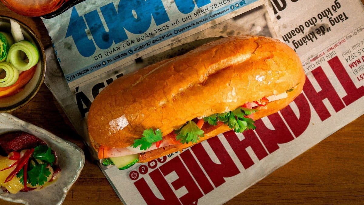 Traditional Vietnamese bánh mì sandwich placed on local newspaper, surrounded by fresh ingredients, offering a cultural and gastronomic glimpse of Việt Nam.