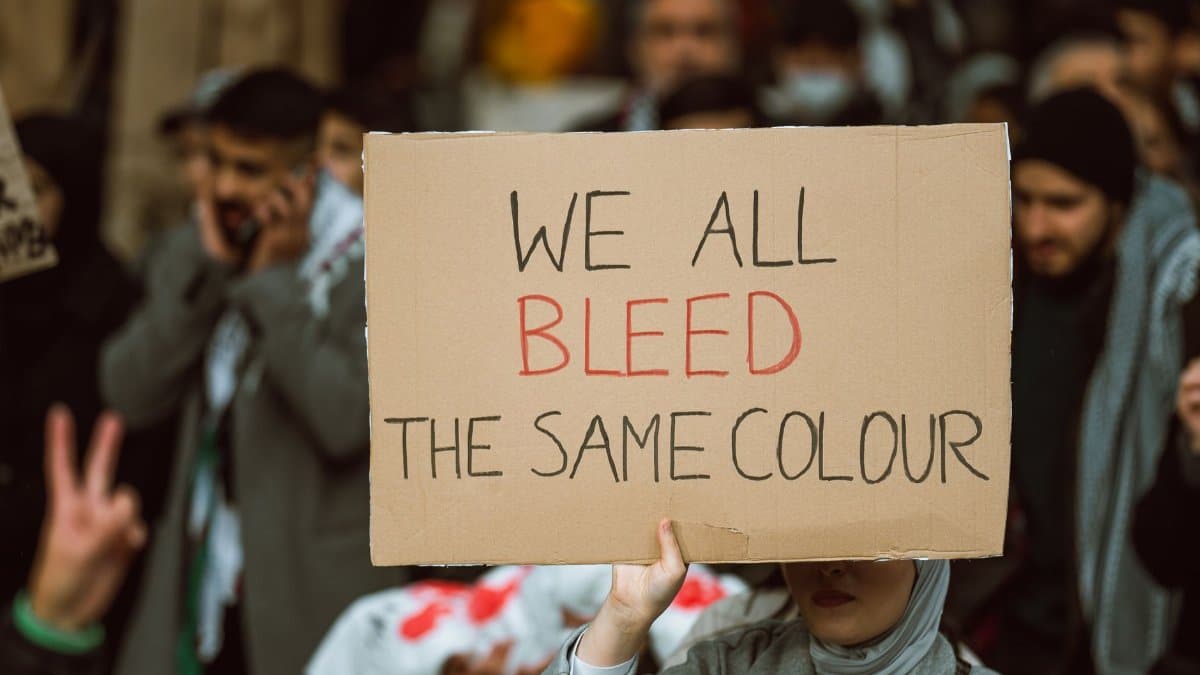 A person holding a protest sign emphasizing unity and equality during a rally.