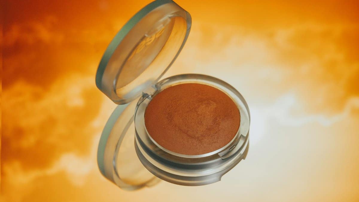 Bronzer illuminating a vibrant orange backdrop, ideal for makeup visuals.