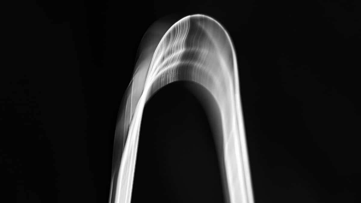 Abstract monochrome image of a dynamic arch shape, showcasing fluidity and motion effect.