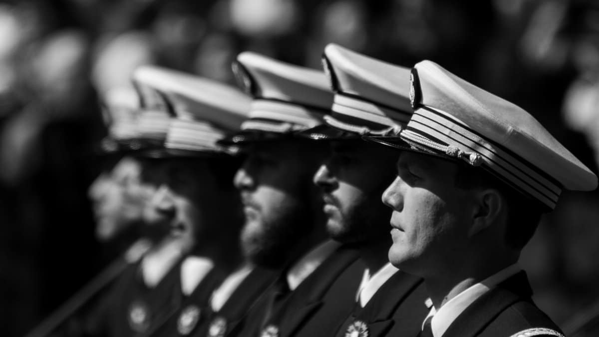 Black and white photo of navy officers in formation during a ceremony, highlighting discipline.