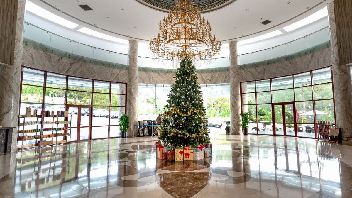 Spacious hotel lobby featuring a beautifully decorated Christmas tree and elegant chandelier.