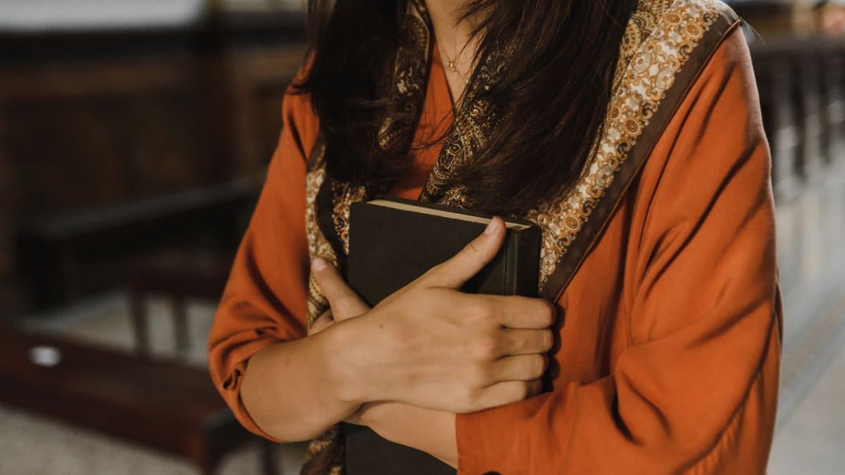Close-up of a woman holding a book in a religious environment, symbolizing faith and spirituality.