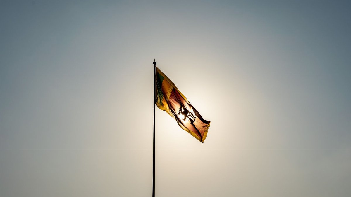 The Sri Lankan flag waves majestically in front of a bright sun in Colombo.