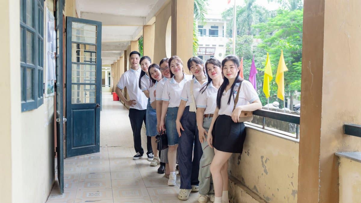 A cheerful group of students posing in a school hallway in Hà Nội, Vietnam, during a sunny day.