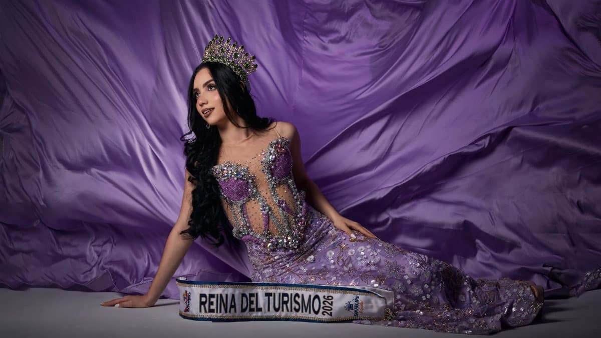 Pageant winner in ornate purple gown with crown, posing elegantly.