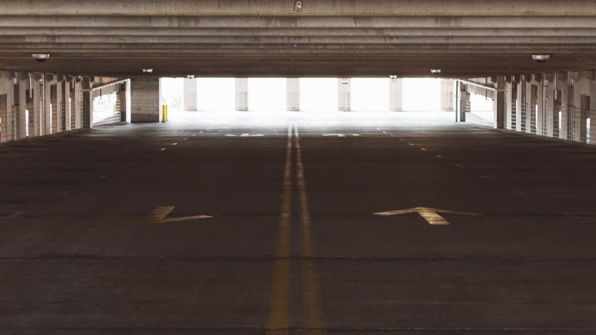 Spacious and empty parking garage interior with directional arrows on the floor, modern architecture.