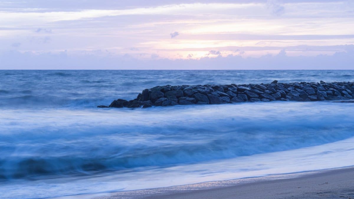 Peaceful ocean waves rolling onto the shore under the twilight sky.