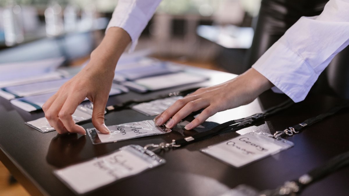 Close-up of hands arranging name tags on a conference table, preparing for a corporate event.