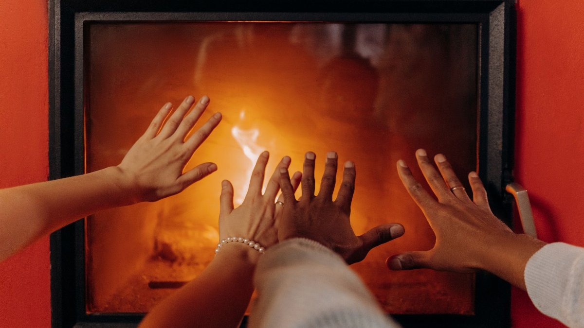 Close-up of hands warming by a cozy fireplace, radiating warmth and comfort.