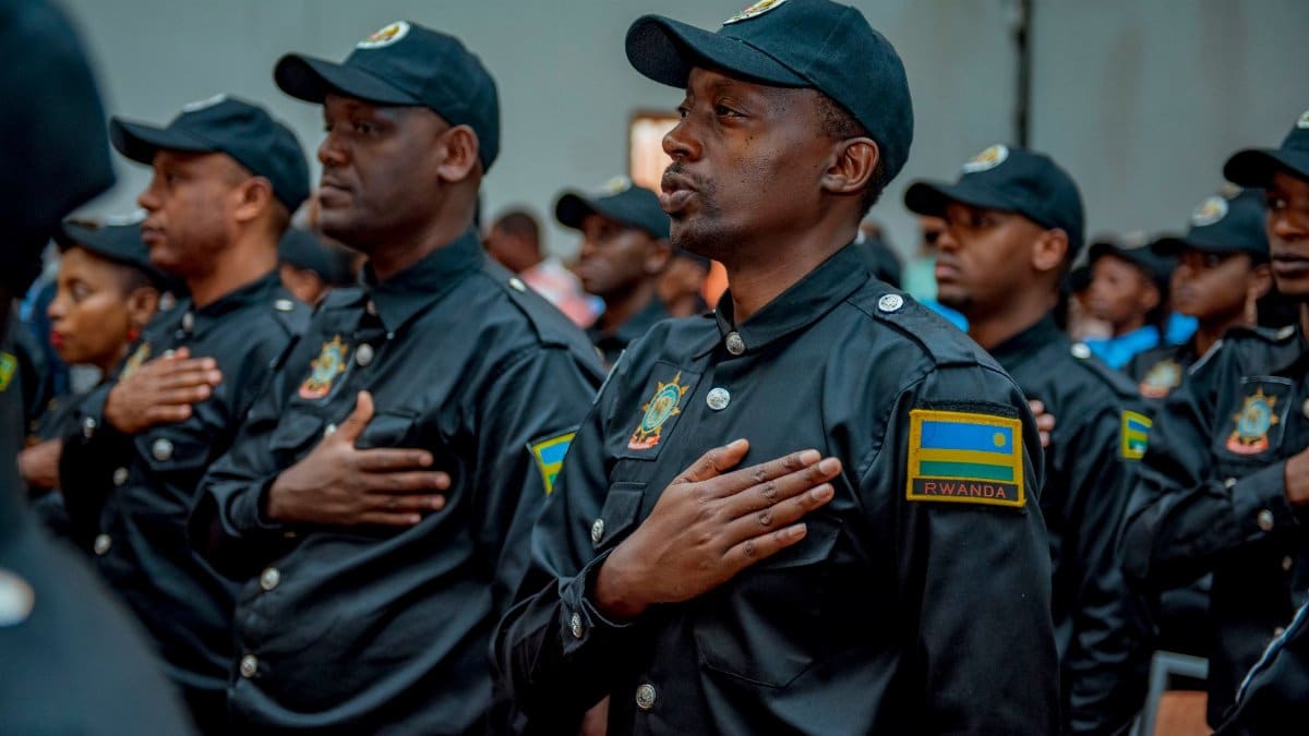 A group of Rwandan police officers in uniform taking an oath during a formal ceremony indoors.