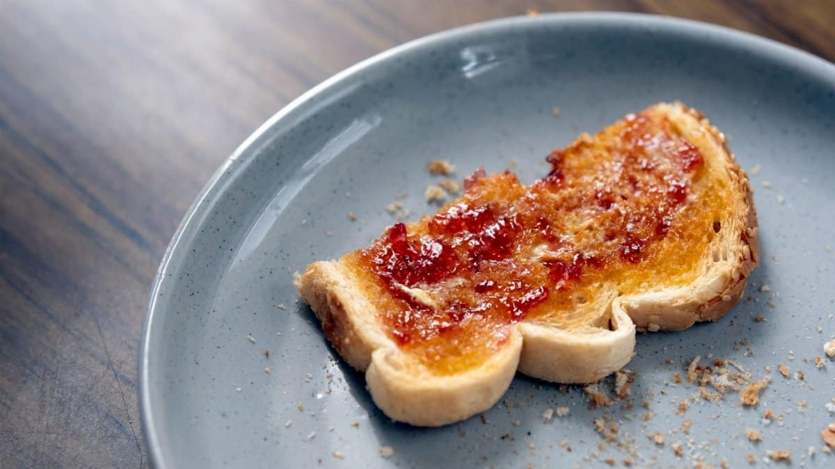 Single slice of toast with jam on a blue plate, perfect for breakfast imagery.