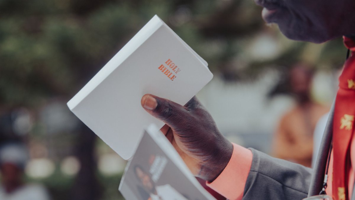 Adult man holding a Holy Bible, participating in an outdoor event, Ibadan, Nigeria.